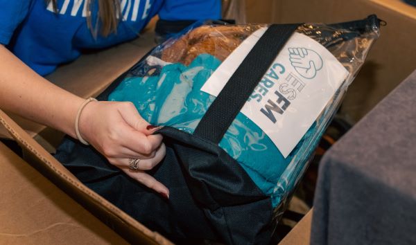 A volunteer packs an ESFM Cares kit, including a blanket and personalized note, to support others.